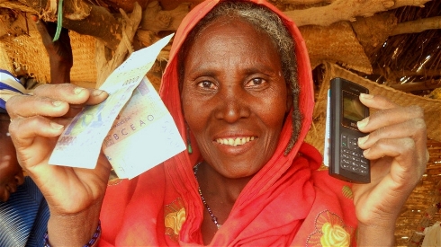 Lady holding cash transfers re-loadable card and a telephone